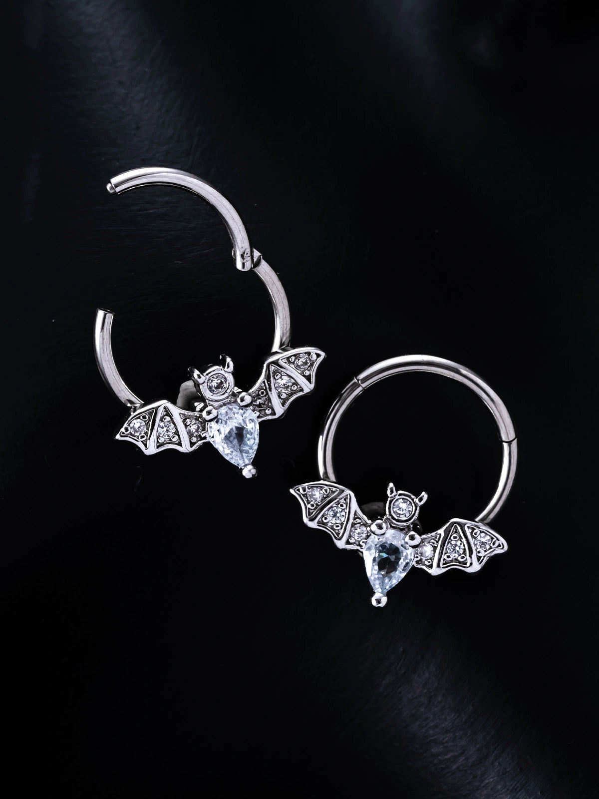 A nose ring featuring a silver bat charm adorned with a clear diamond.